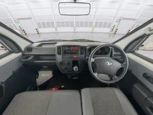 Interior kabin Daihatsu Gran Max, menampilkan dashboard sederhana, setir, dan kursi penumpang depan yang fungsional.